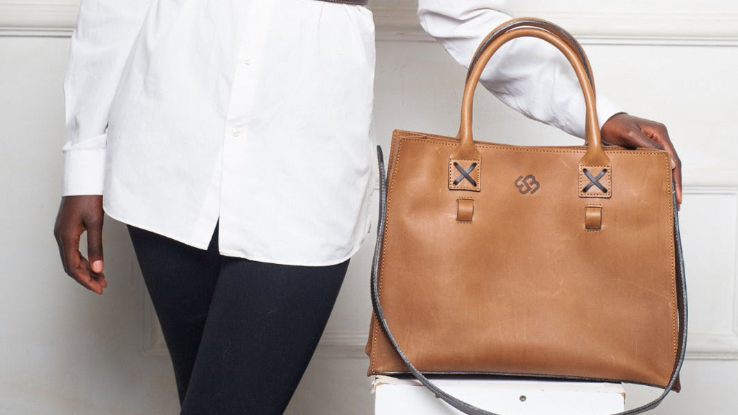 Woman holding a brown handbag against a white background