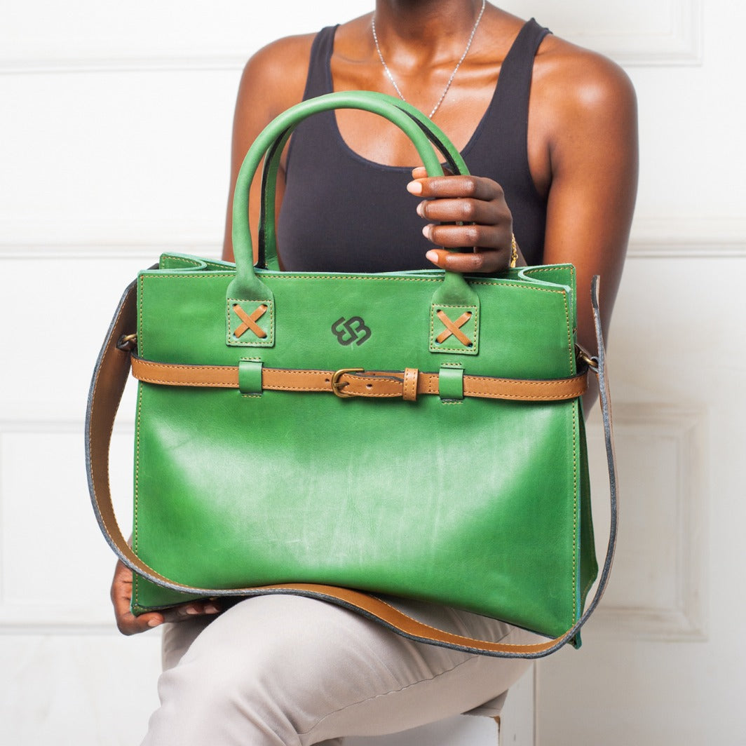 Woman holding a green handbag with a visible brand logo against a white background