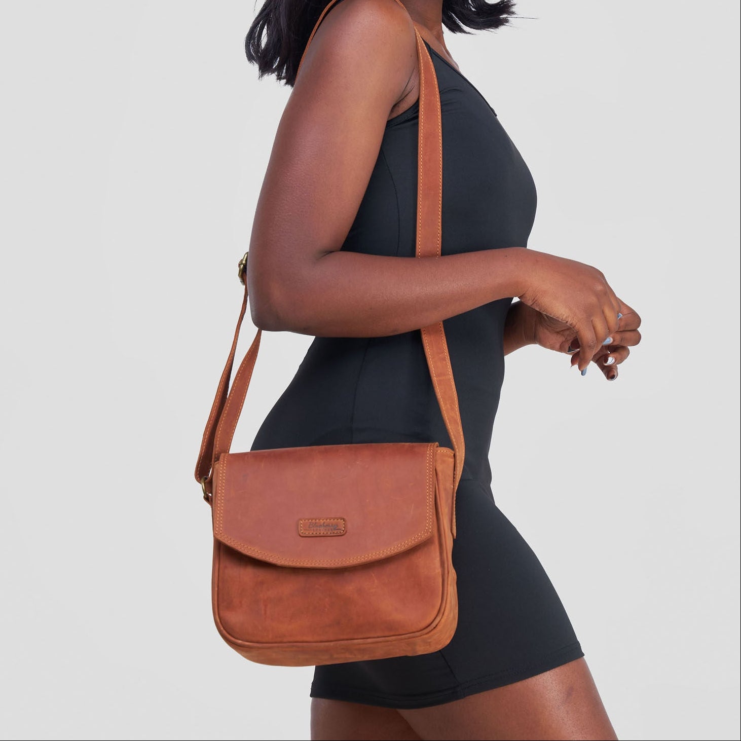 Woman carrying a brown leather bag on a plain background