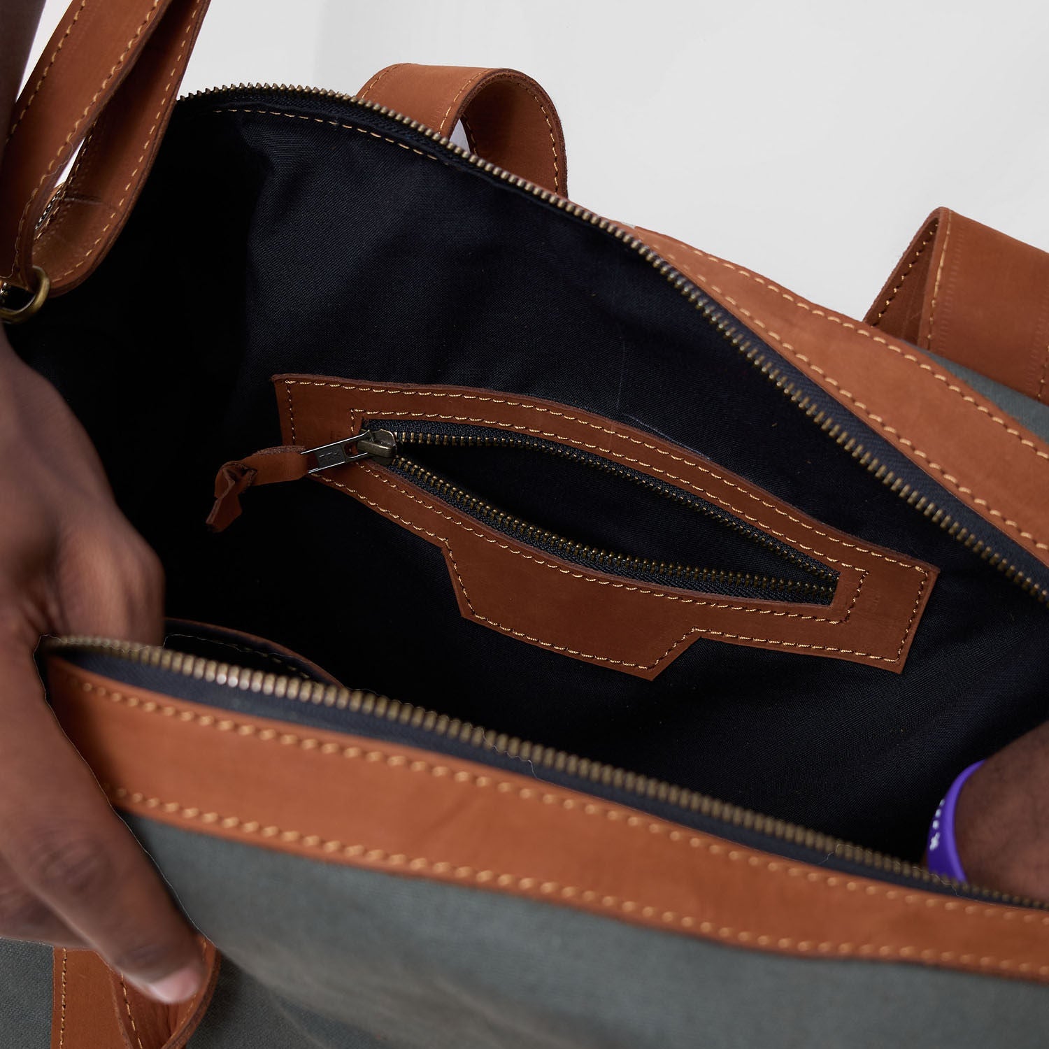 Close-up of a brown and gray bag with a zipper being opened.