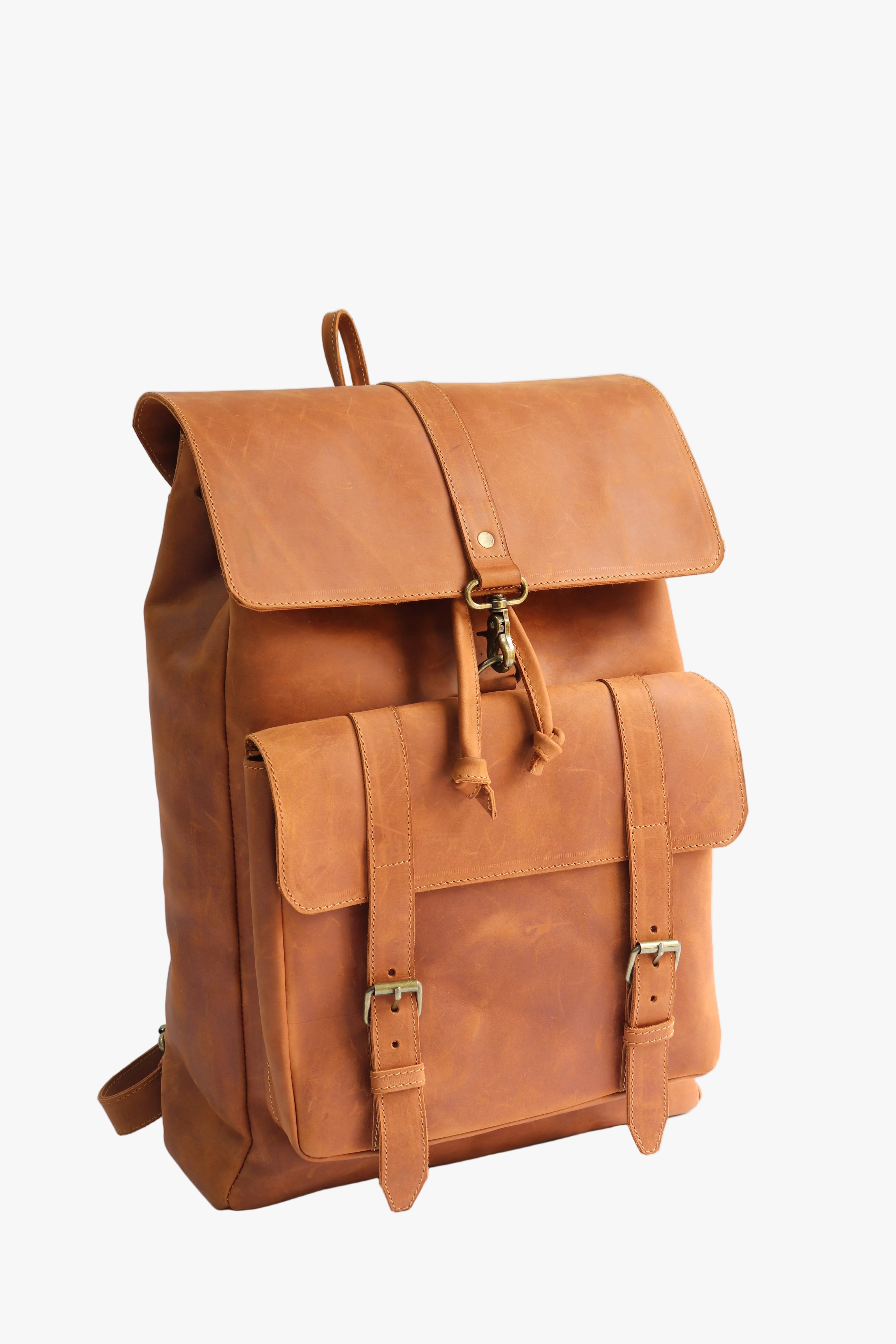 A tan leather backpack with a front flap pocket, buckle straps, and brass-tone hardware, photographed on a clean white studio background.