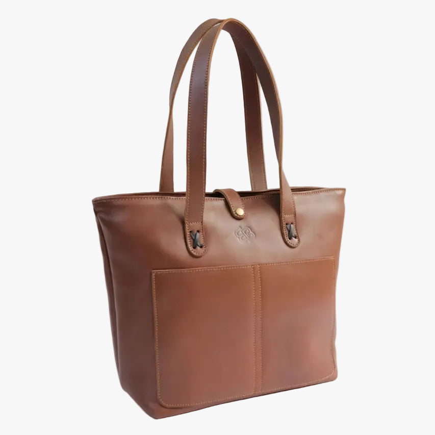 A brown leather tote bag with dual shoulder straps, a front slip pocket, and a small gold-tone logo emblem on the front, photographed against a plain white background.