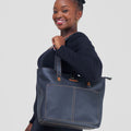 Woman holding a large blue tote bag against a plain background