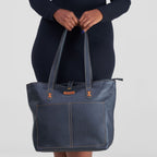 Person holding a blue denim handbag against a white background