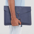 Person holding a blue leather clutch bag against a light background
