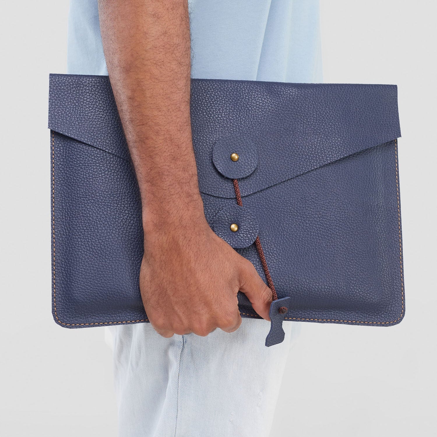 Person holding a blue leather clutch bag against a light background