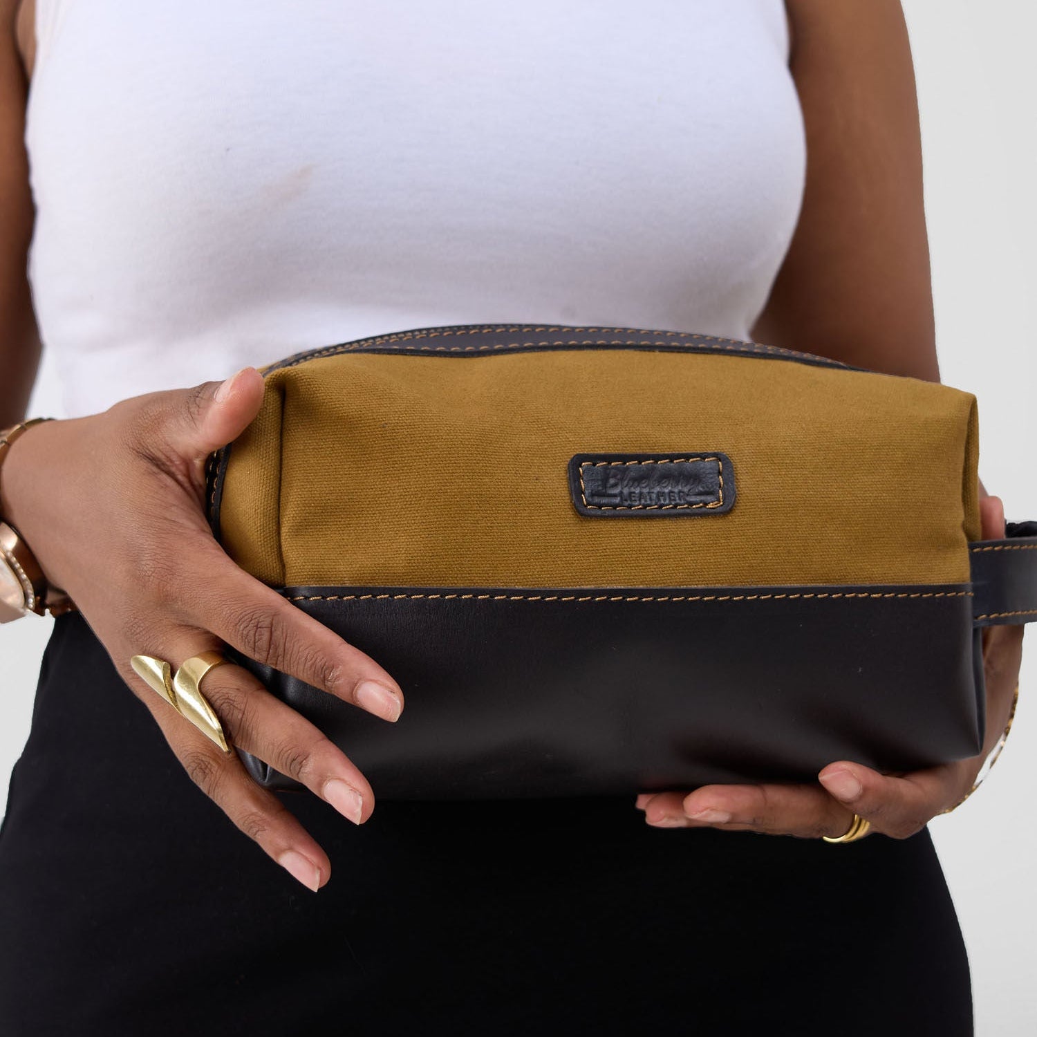 Person holding a brown and black clutch bag against a white background