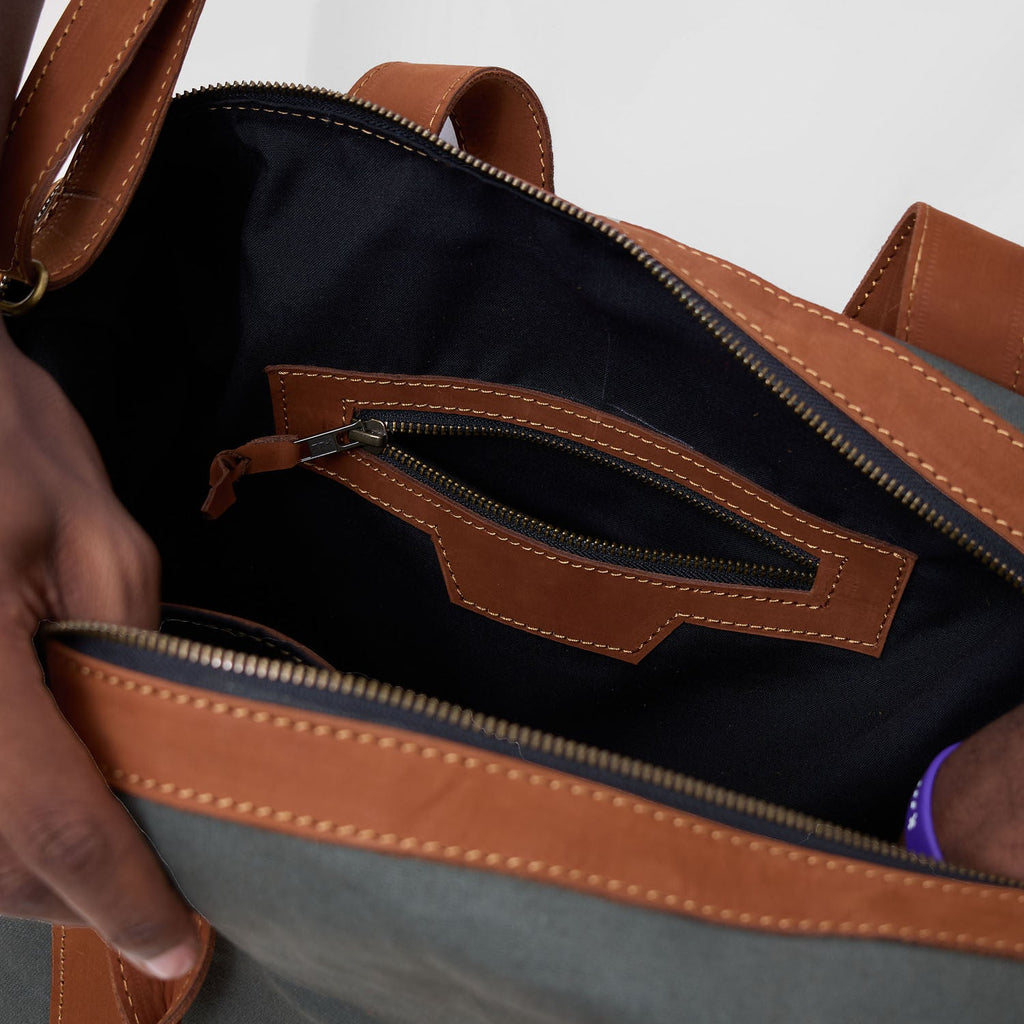 Close-up of a brown and gray bag with a zipper being opened.