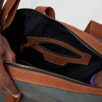 Close-up of a brown and gray bag with a zipper being opened.