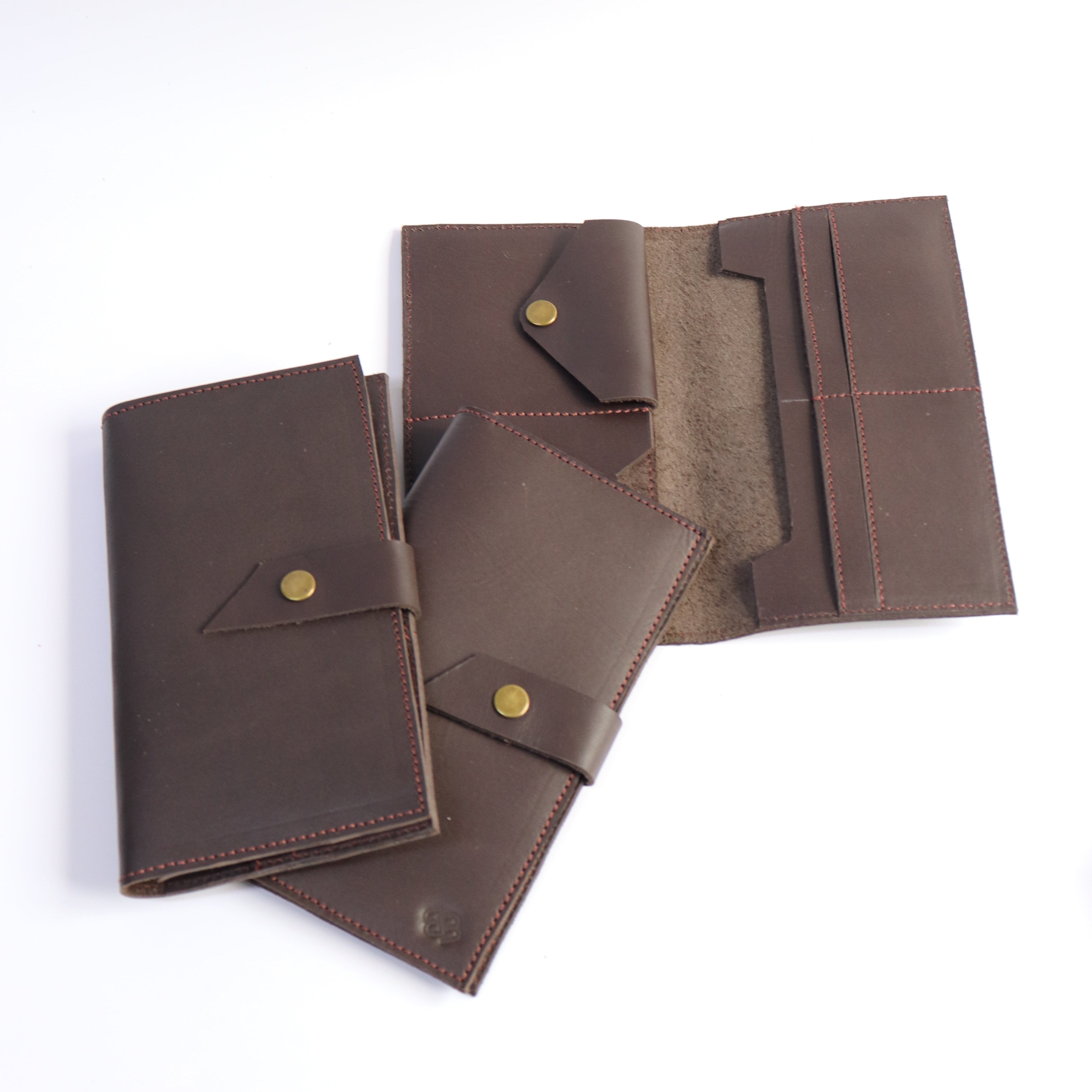 Three dark brown leather organizer wallets with brass snap buttons, shown on a plain white background, with one open to reveal interior card slots.
