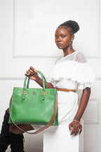 Model holding a forest green Blueberry Leather Duma cowhide tote bag with brown accents and adjustable strap.