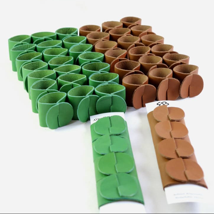 A set of small cylindrical plastic clips or fasteners arranged in two color groups: green on the left and brown on the right, with two additional pieces shown in front on a white background.